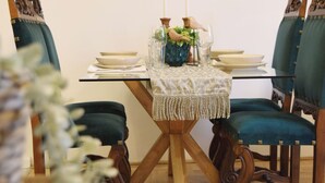 Un comedor con una mesa de madera, sillas tapizadas de verde y un cuadro en la pared.