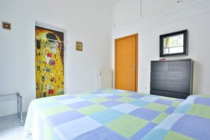 A bedroom with a bed, a wooden door, a radiator, and a framed picture on the wall.