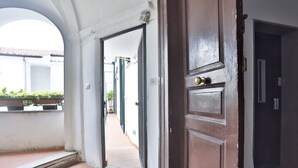 An open doorway leading to a corridor with a tiled floor and a view of a building with a tiled roof.