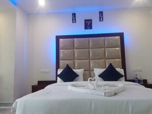Une chambre d’hôtel avec un grand lit, une tête de lit rembourrée et deux coussins décoratifs.