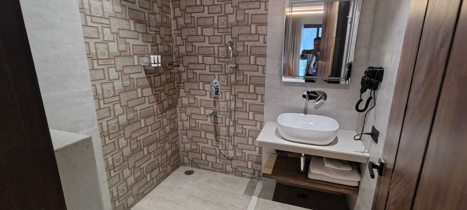 A bathroom with a shower, a sink, and a mirror.