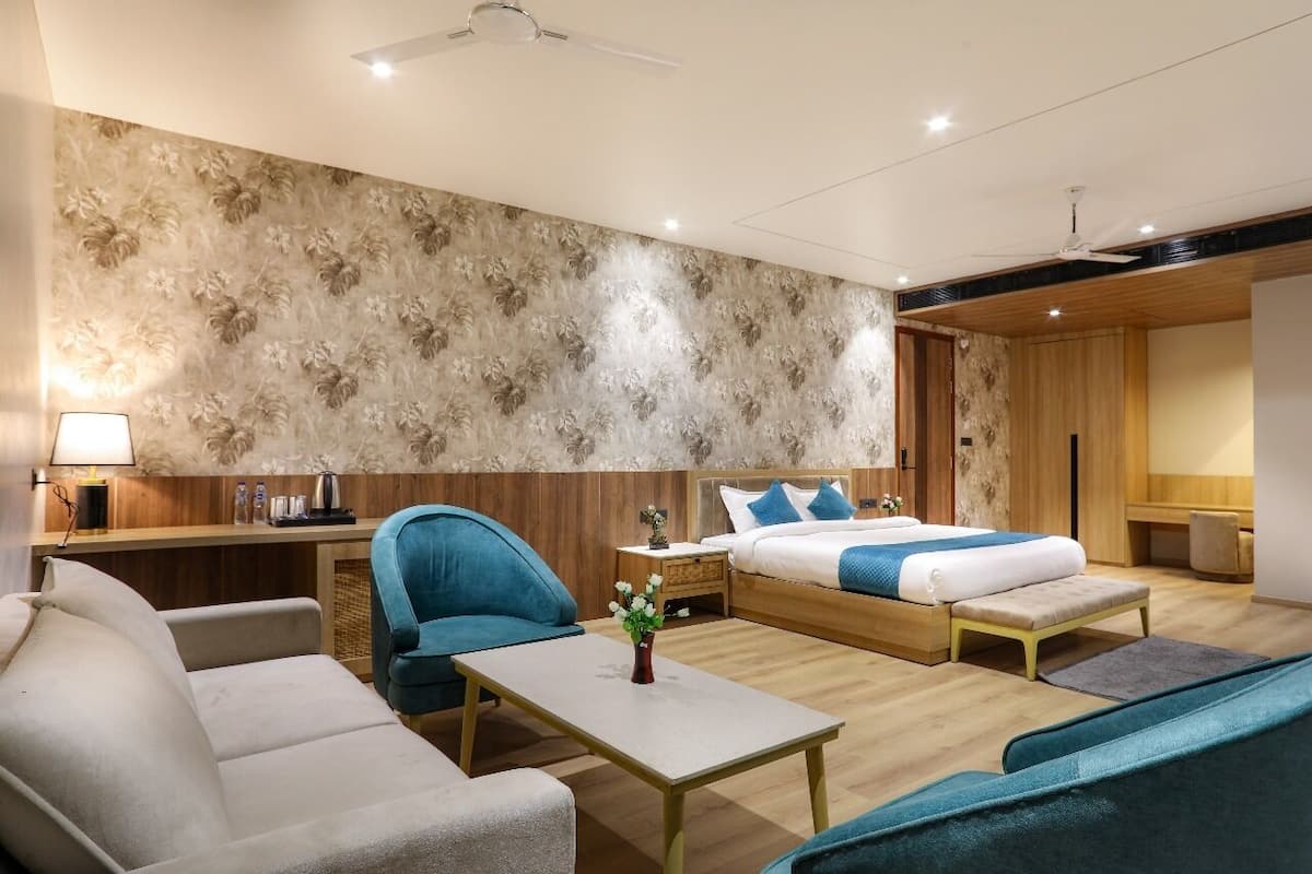 A modern hotel room with a bed, sofa, and a small table with a vase of flowers.