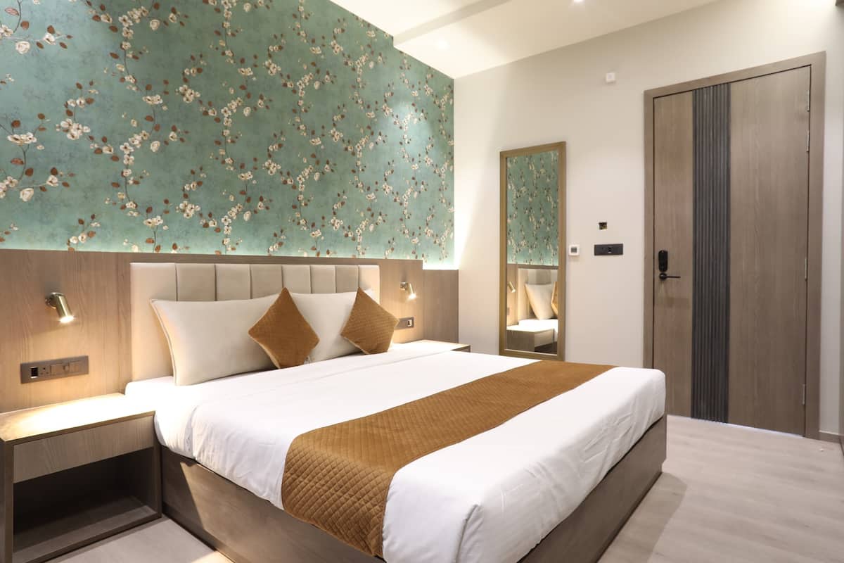 A modern hotel room with a large bed, a nightstand, a mirror, and a wardrobe.