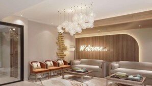 Ein modernes Wohnzimmer mit einem 'Welcome'-Schild, zwei Sofas, einem Couchtisch und einer dekorativen Chandelier.
