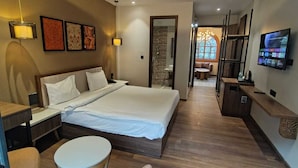 Ein modernes Hotelzimmer mit einem großen Bett, Nachttischen, einem Schreibtisch und einem an der Wand befestigten Fernseher.