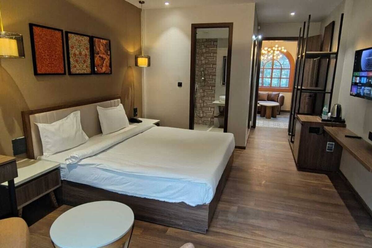 A modern hotel room with a large bed, bedside tables, a desk, and a TV mounted on the wall.