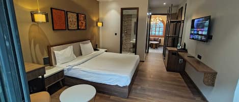 Una habitación de hotel moderna con una cama grande, mesitas de noche, un escritorio y un televisor montado en la pared.