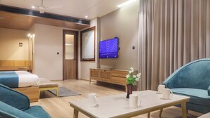 Ein modernes Hotelzimmer mit Bett, einer Couch, einem Tisch mit Tassen, einem Fernseher und einem Vorhang.