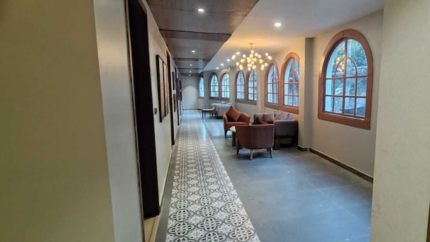 Ein Flur mit gemustertem Boden, Rundbogenfenstern und einer Sitzecke mit Sofas.