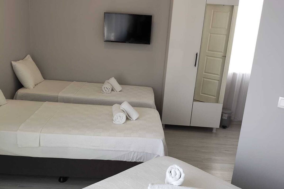 Une chambre d’hôtel avec deux lits, un téléviseur à écran plat, une armoire et une porte donnant sur une autre pièce.