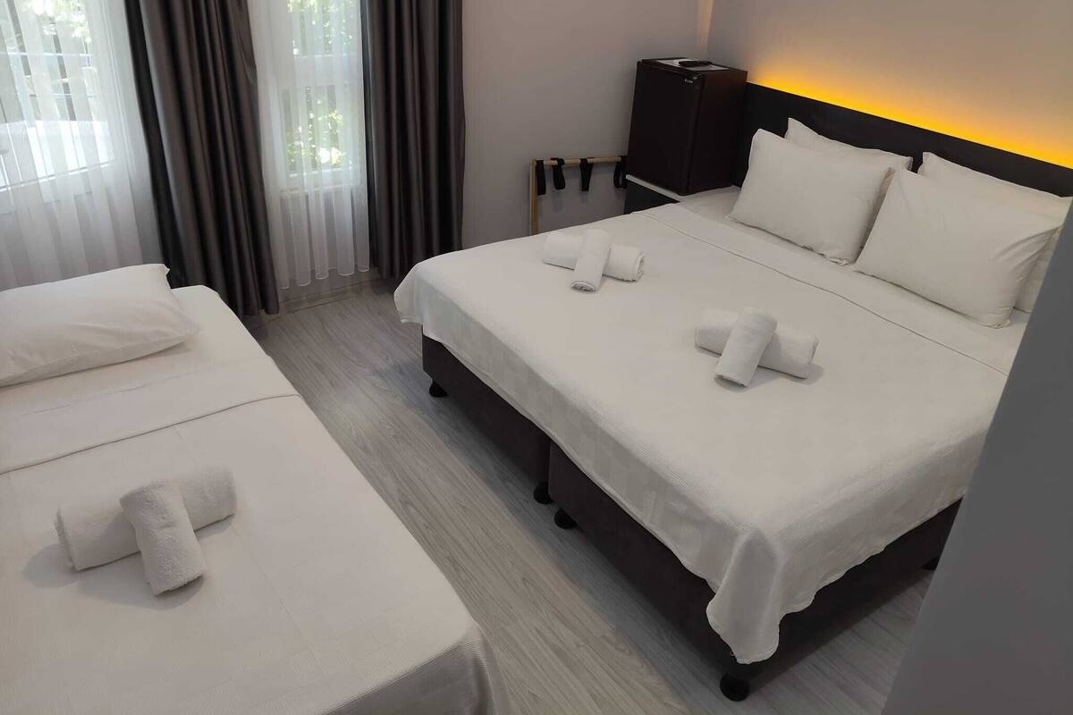Une chambre d’hôtel avec un lit, une table de chevet, une lampe et une fenêtre avec des rideaux.
