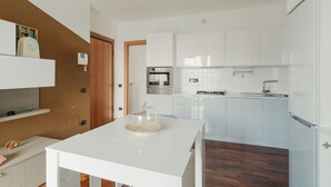 Una cocina moderna con armarios blancos, horno integrado y un lavamanos.