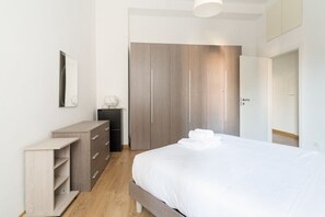 A bedroom with a bed, a wardrobe, a dresser, and a mirror.