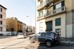 A street view with parked cars, buildings, and a pedestrian crossing.