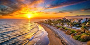 A coastal sunset view with a beach, road, and residential buildings. - Luxury Apartment in Marbella with Terrace, Garden and Pool-5 min from the Beach (Marbella)