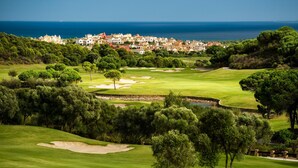 A golf course with a view of the ocean and a residential area in the background.