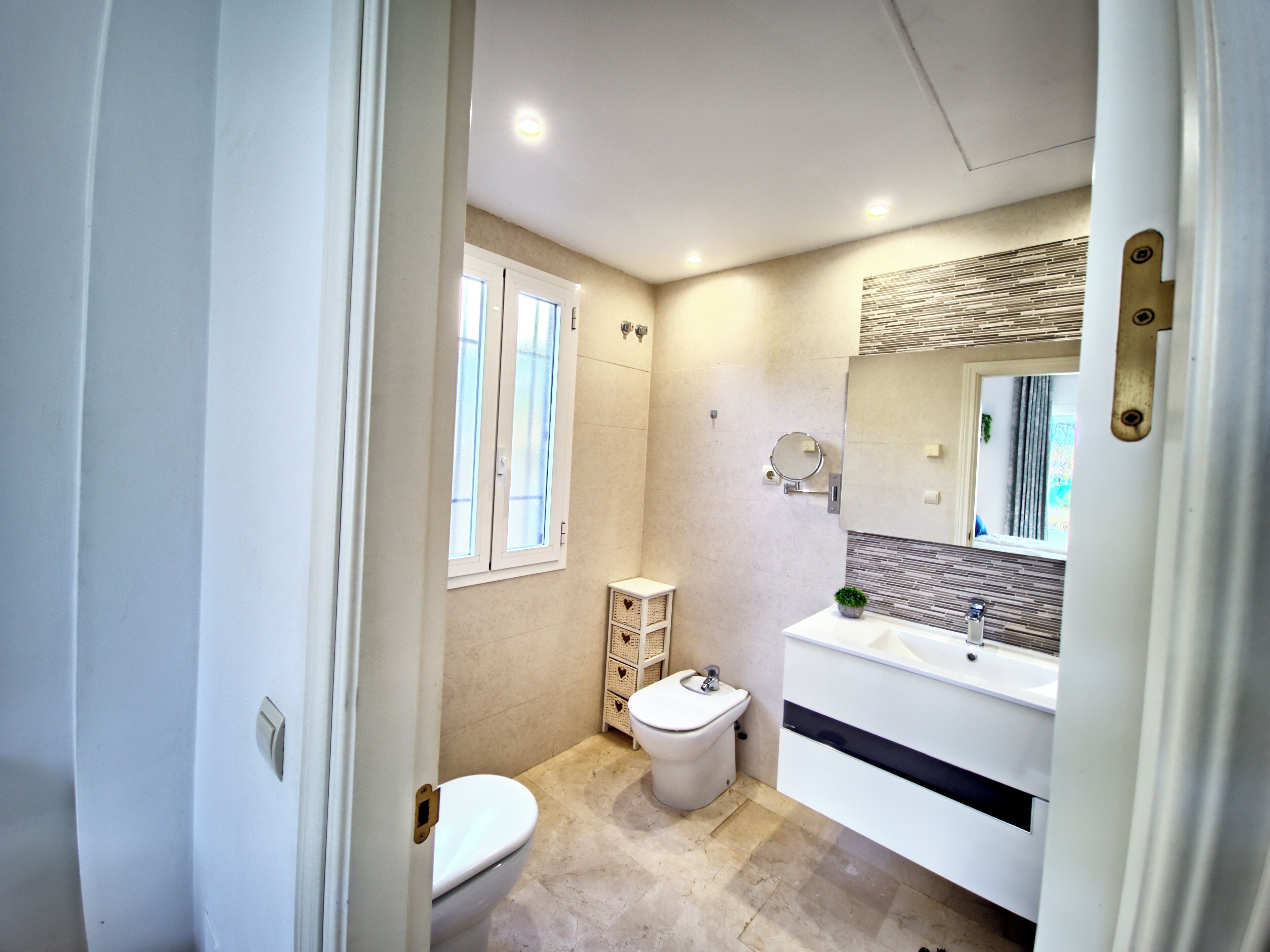 Une salle de bain moderne équipée de toilettes, d’un bidet, d’un meuble-lavabo et d’un grand miroir.