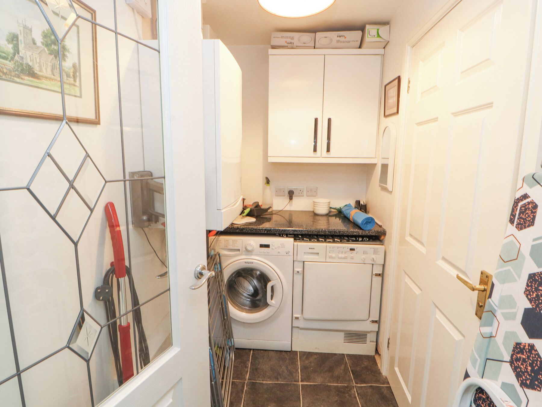 A compact laundry room with a washing machine, dryer, and cabinets above.