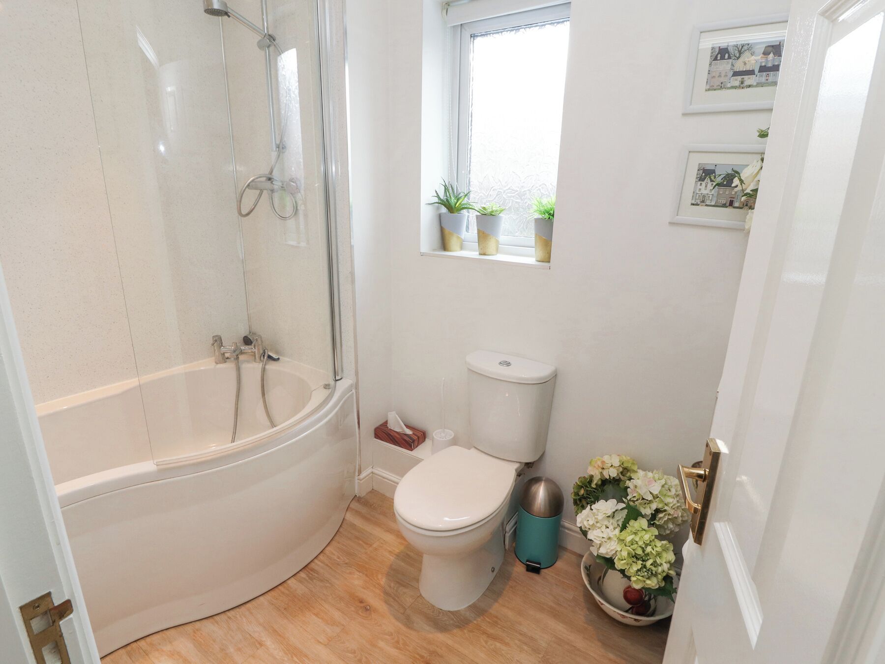 A bathroom with a bathtub, toilet, and a window with plants.