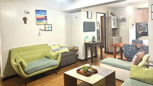 A living room with a green sofa, a coffee table, and a dining area with a table and chairs. - Spacious 3BR Senja Pasig Home - Sleeps Up To 9! (Pasig)