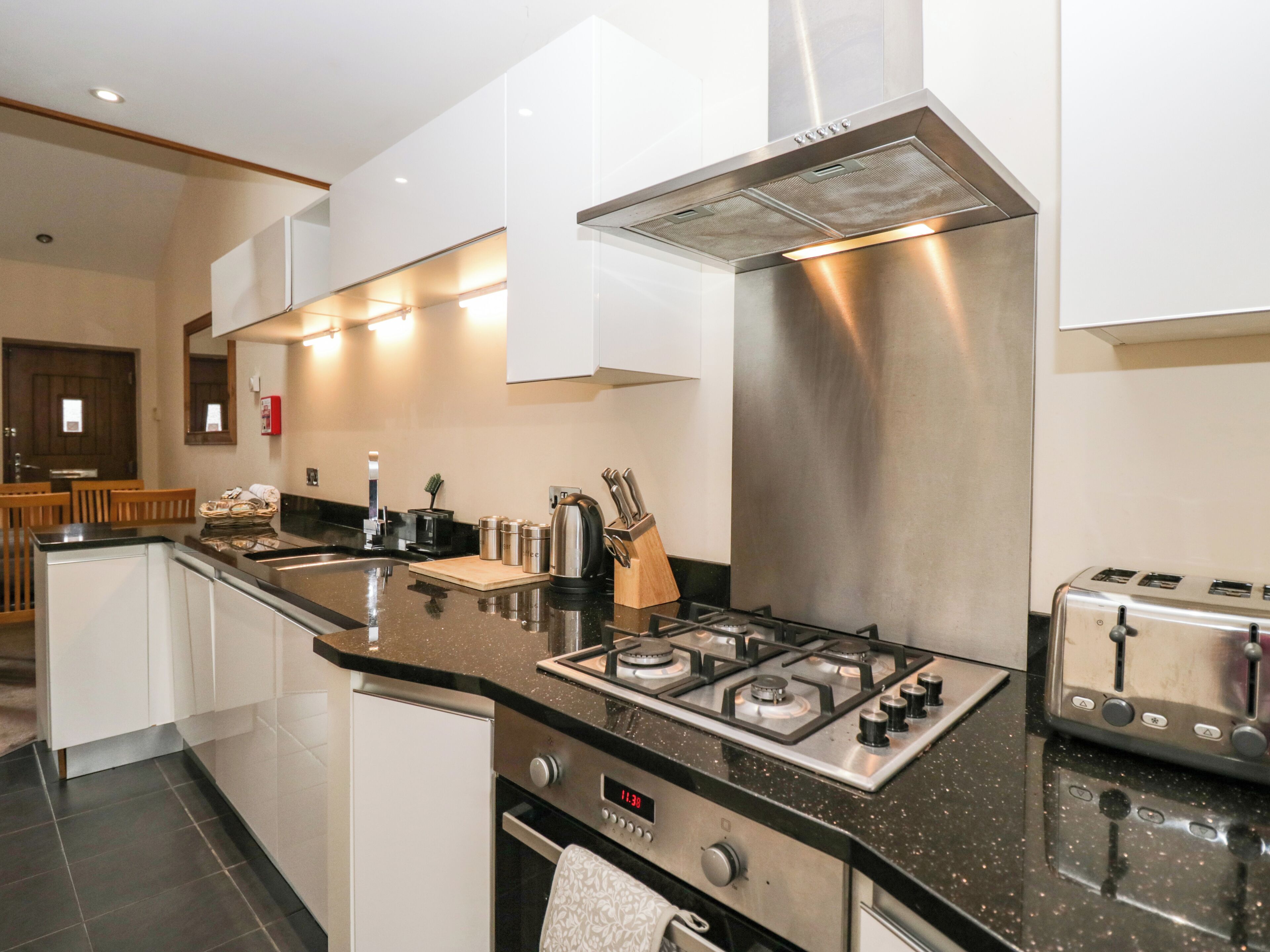 A modern kitchen with a stainless steel range hood, a gas stove, a built-in oven, and a toaster.