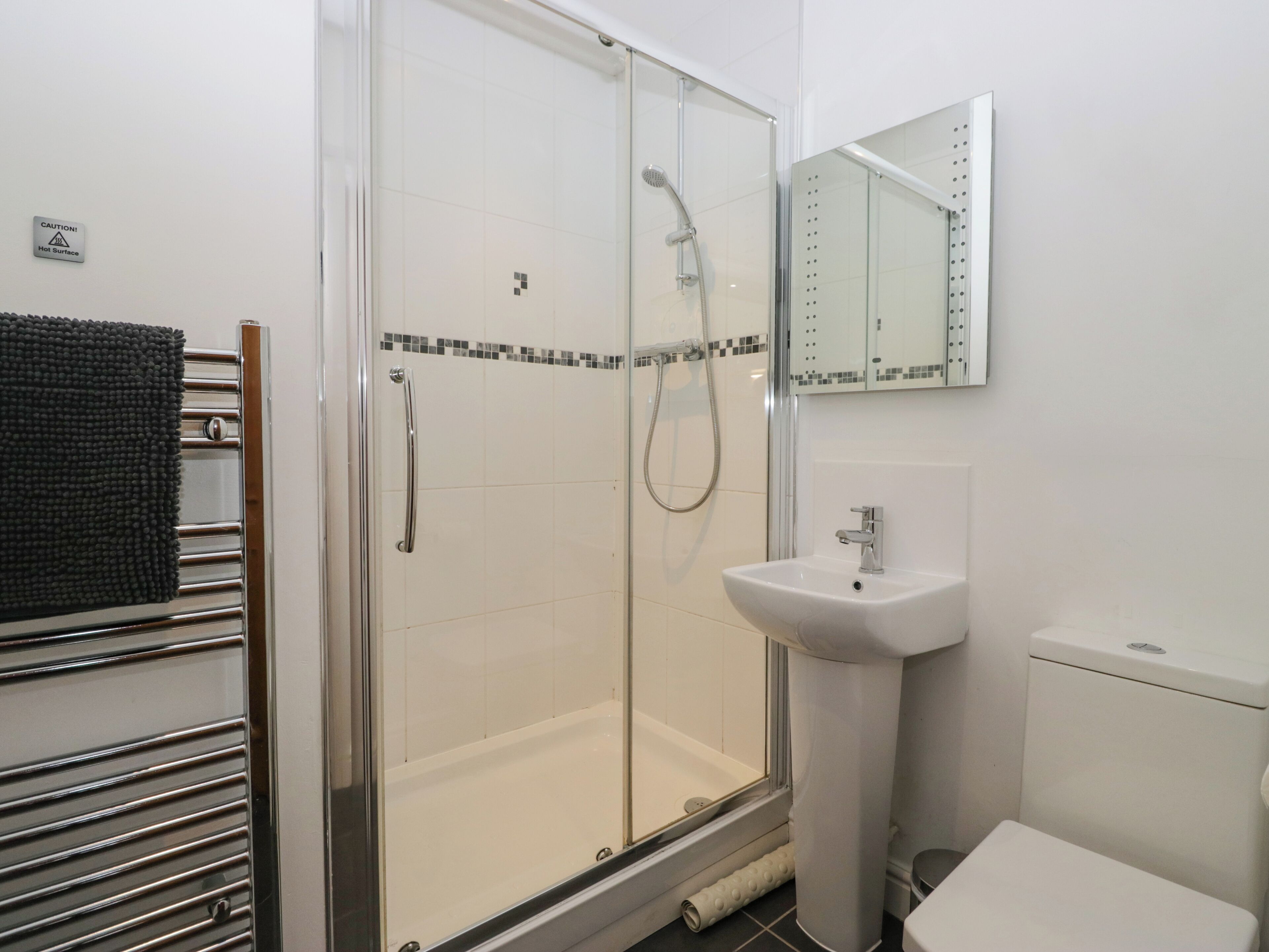 Ein modernes Badezimmer mit einer Duschkabine, einem weißen Waschbecken und einer Toilette.
