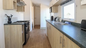 Una cucina moderna con mobili in legno, piano cottura a gas, lavello e una finestra che lascia entrare luce naturale.