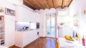 A modern kitchen with white cabinetry, a gas stove, an oven, and a washing machine.