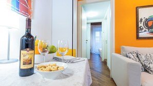 A dining area with a table set for two, featuring a bottle of wine, glasses, and a bowl of snacks.