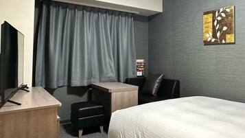 Une chambre d’hôtel avec un lit, un bureau, une chaise, une petite table et un téléviseur.