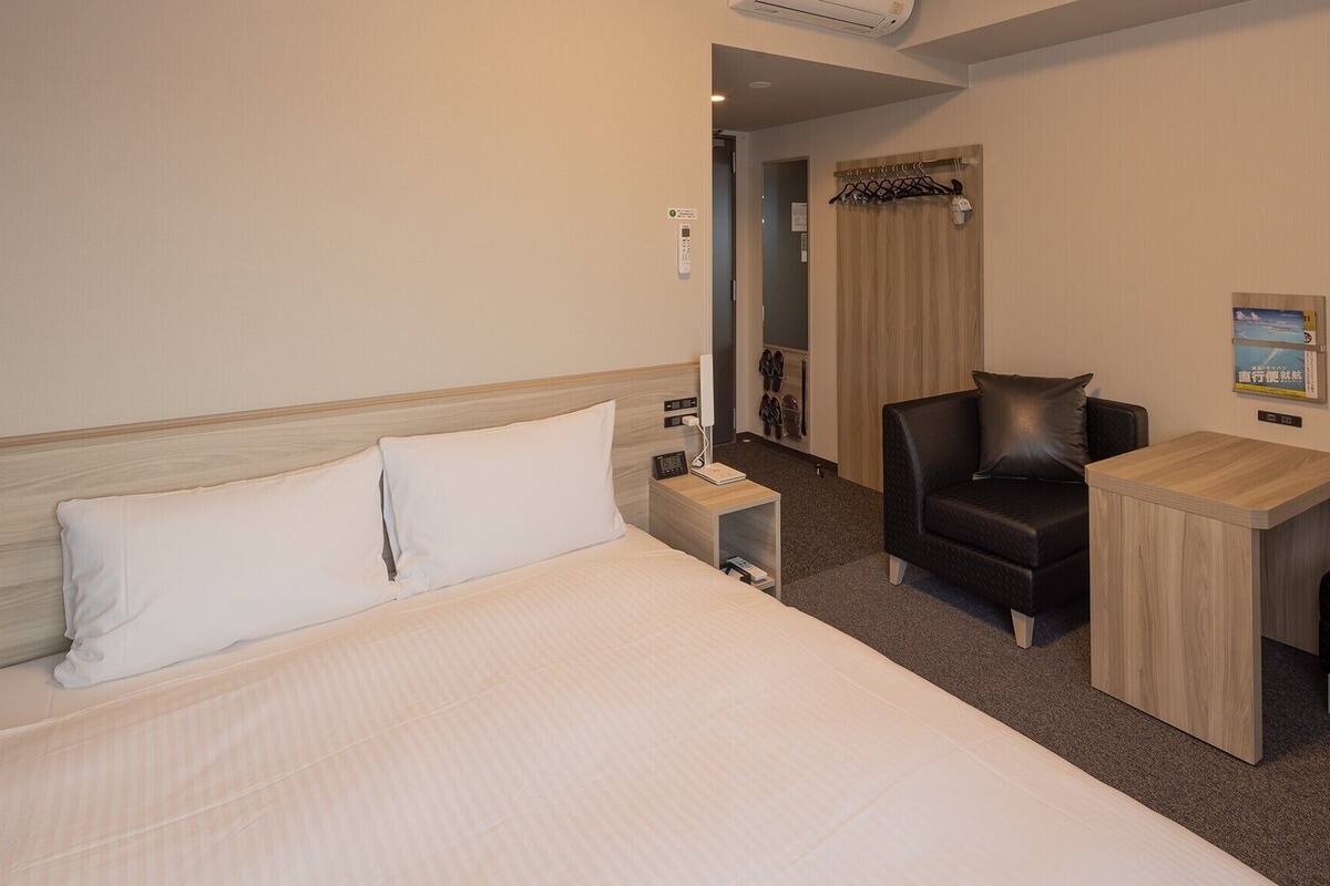 Une chambre d’hôtel avec un lit, un bureau, une chaise et une petite table.