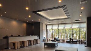Un vestíbulo amplio con una recepción, zona de estar y grandes ventanales con vistas al exterior.