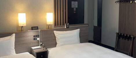 Habitación de hotel con dos camas, lámparas de noche, mesitas de noche, un espejo y un armario.