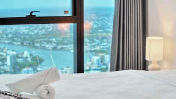 A hotel room with a bed, a window with a city view, and a lamp.