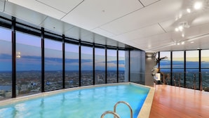 A rooftop infinity pool with a city view, large windows, and a wooden deck. - Horizon Haven with Panorama view with Free parking (Brisbane City)