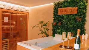 A spa room with a wooden sauna, a large bathtub, and a wall-mounted sign that reads "LOMY." - Cottage Lomy with Sauna and Balneo (Lamballe-Armor)