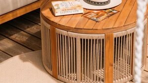 A round wooden table with a woven base, a white hat, and a magazine on it. - Cottage Lomy with Sauna and Balneo (Lamballe-Armor)