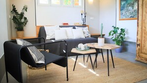 A modern living room with a sofa, a black armchair, a small wooden table, and a potted plant. - Venez Chez Vous Appartement Aux Premières Loges (Sévrier)