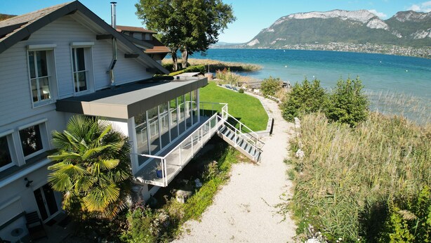 A modern house with a glass balcony overlooking a lake and mountains. - Venez Chez Vous Appartement Aux Premières Loges (Sévrier)