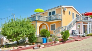 A two-story building with a balcony, outdoor seating, and a staircase leading to the upper floor. - Apartment in Croatia near Adriatic Coast (Senj)