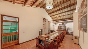 A spacious dining area with a long wooden table, multiple chairs, a wooden cabinet, and a ceiling fan. - Taomi Mountain Lodge (Puli)