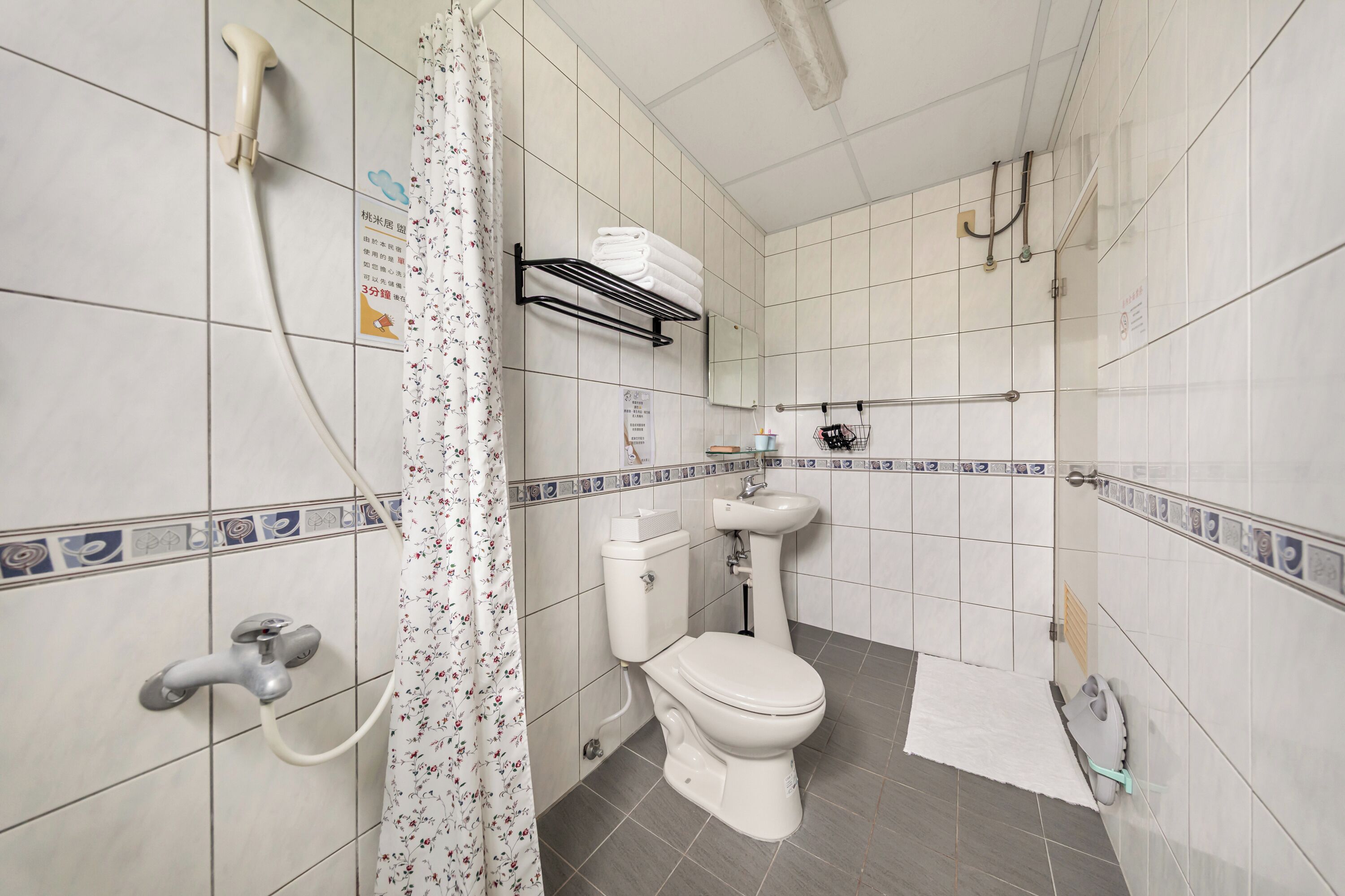 Une salle de bain équipée de toilettes, d’un lavabo, d’une douche et d’un porte-serviettes.