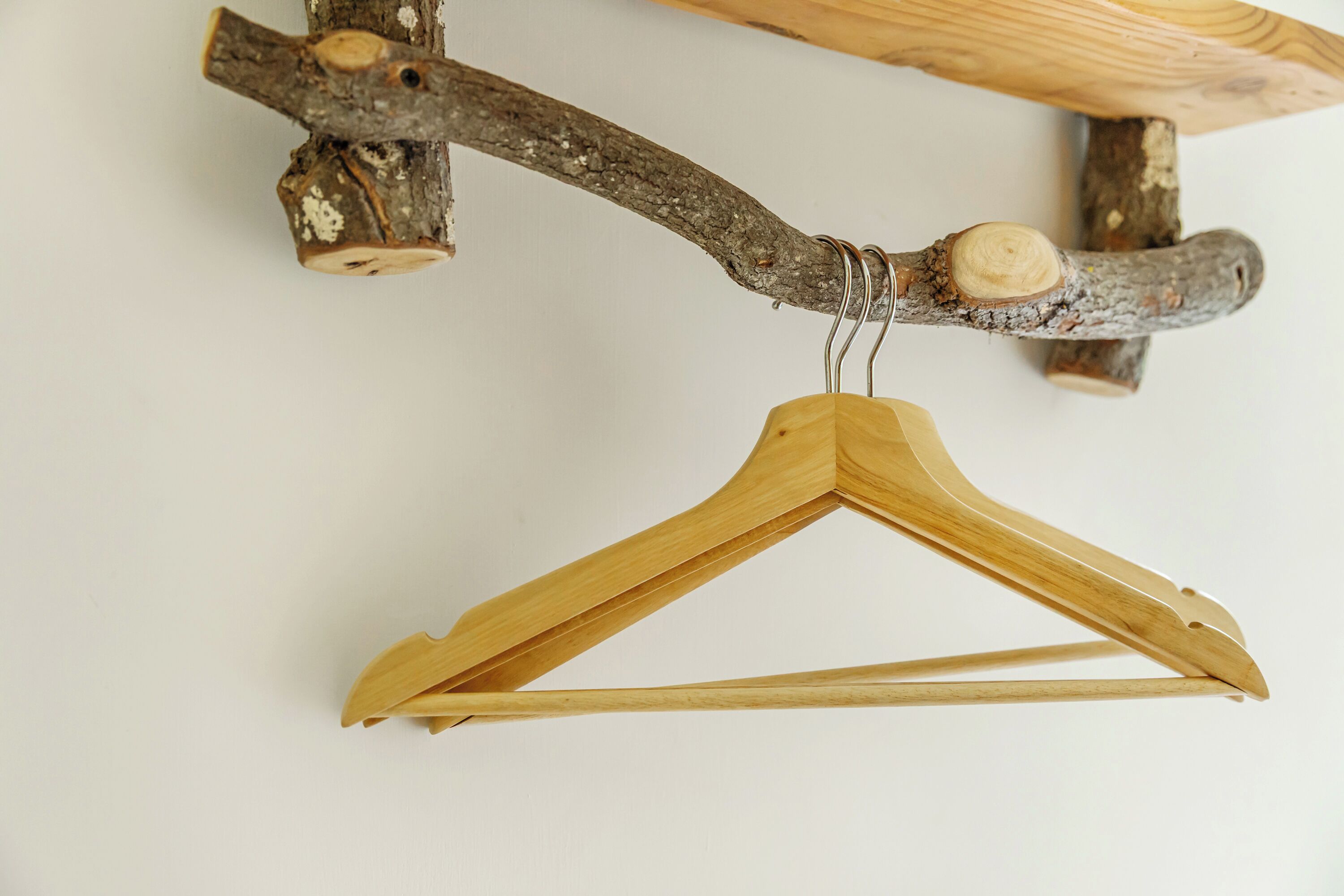 A wooden hanger with a natural finish, attached to a rustic wooden beam.