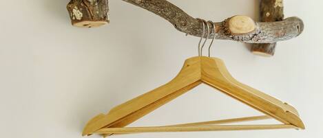 A wooden hanger with a natural finish, attached to a rustic wooden beam.
