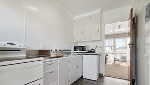 A modern kitchen with white cabinets, a microwave, and a stove. - Flamingo Motel (New Plymouth)