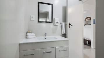 A modern bathroom with a white sink, mirror, and towel rack.