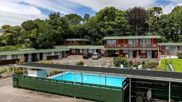 A motel with a pool, multiple rooms, and a two-story building with a balcony.