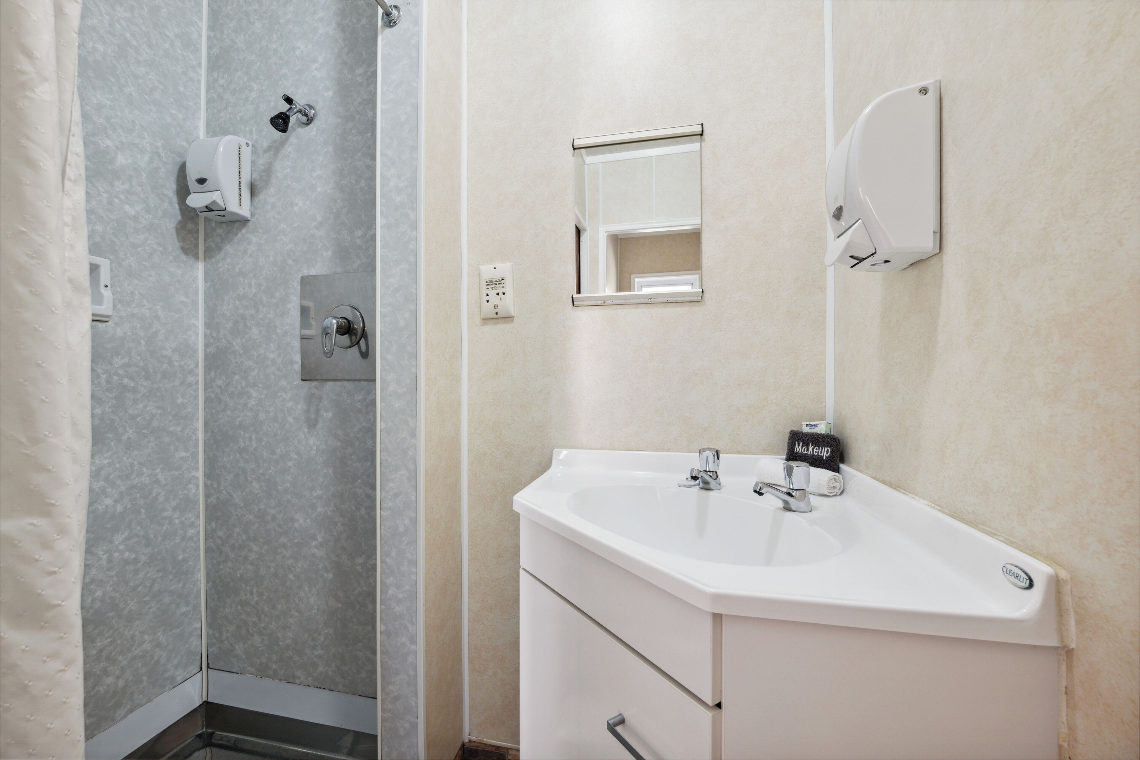 A bathroom with a white sink, a mirror, and a shower area.