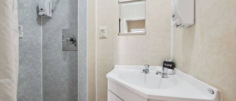 A bathroom with a white sink, a mirror, and a shower area.