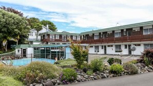 A motel with a swimming pool, multiple-story buildings, and a landscaped garden. - Flamingo Motel (New Plymouth)